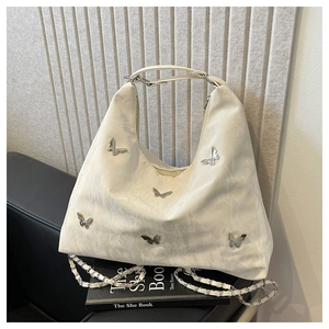 Close-up of cream white pleated tote bag featuring silver butterfly metal ornaments