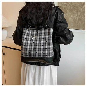 Detailed back view of a plaid backpack with bow embroidery and metallic accent on model