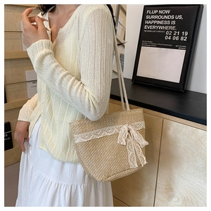 Detail of straw woven tote bag featuring delicate white lace trim and bow decoration