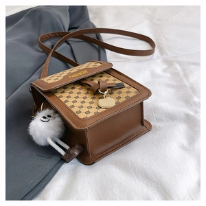 Détail d'un sac bandoulière carré en similicuir marron avec imprimé mode et breloque peluche