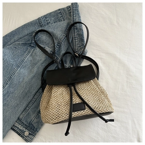 Detail of woven straw backpack with black leather straps on denim background
