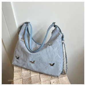 Detail of light blue hobo bag with silver butterfly charms and pleated texture finish