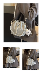 Detail of silver metallic drawstring bucket bag with woven strap and plush charm