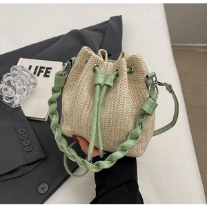 Detail of beige straw bucket bag with green leather drawstring and woven handle