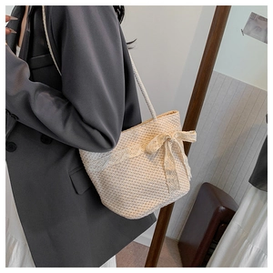 Close-up of beige woven straw bag with lace bow detail and shoulder strap for summer beach