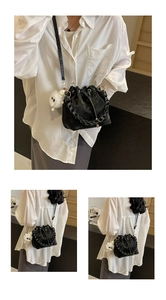 Black drawstring bucket bag with woven chain handle and cute white plush charm detail