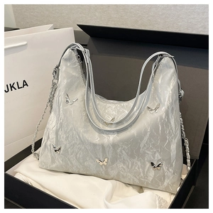 Close-up of metallic butterfly ornaments on silver pleated tote bag in gift box
