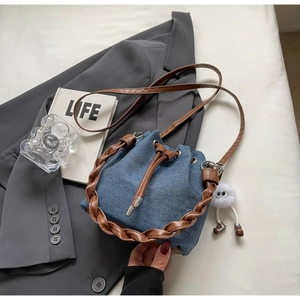 Detail of blue denim bucket bag with drawstring closure and brown braided handle