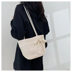 Detail of woven straw tote bag featuring white lace trim and decorative ribbon bow
