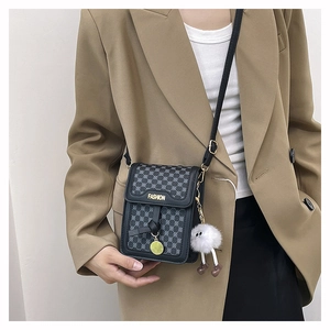 Vue détaillée du mini sac bandoulière noir avec plaque dorée porté par un mannequin