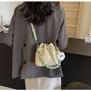 Detail of straw bucket bag with drawstring closure and green adjustable shoulder strap