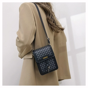 Détails du sac de téléphone noir à motif géométrique porté en bandoulière par un modèle