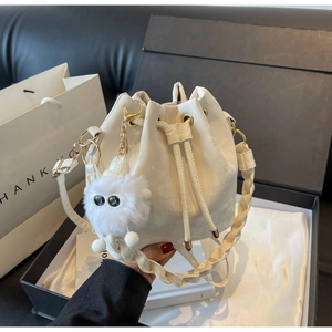 Detail of white drawstring bucket bag with braided strap and plush monster charm