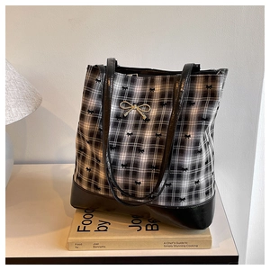 Detail of checkered tote bag with black bow embroidery and gold metal bow charm