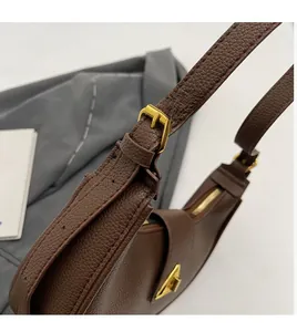 Gros plan d'un sac à bandoulière en cuir marron avec boucle triangulaire dorée réglable
