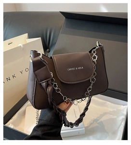 Brown leather shoulder bag with floral chain detail inside a gift box and paper bag