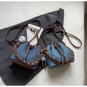 Detail of denim bucket bags featuring woven handles, drawstring closures, and plush charms