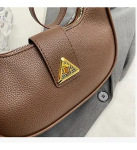 Détail d'un sac à main en cuir marron à motif litchi avec boucle en métal doré