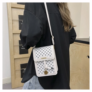 Détail du mini sac bandoulière crème avec monogramme noir et pendentif doré élégant
