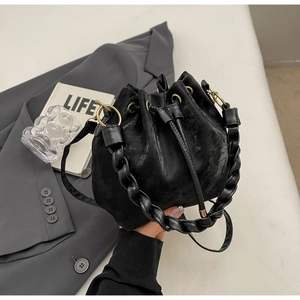 Detail of black velvet bucket bag with drawstring closure and thick braided handle with gold rings