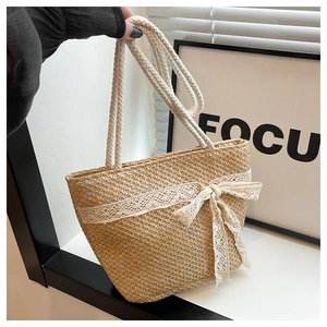 Detail of hand-woven straw tote bag featuring creamy white lace and large ribbon bow
