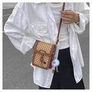 Détail du petit sac carré vintage marron imprimé avec un porte-clés pompon en peluche