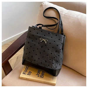 Detail of grey knit tote bag with polka dots, bow embroidery and gold metal charm