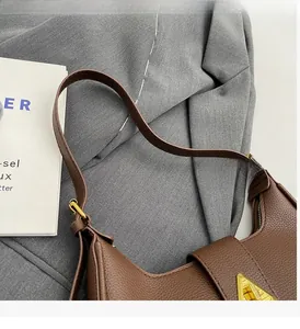 Détail d'un sac à main en cuir grainé marron foncé avec un fermoir triangle doré élégant