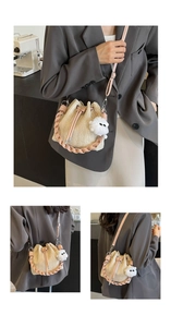 Detail of straw bucket bag featuring pink leather straps and a cute plush pompom charm