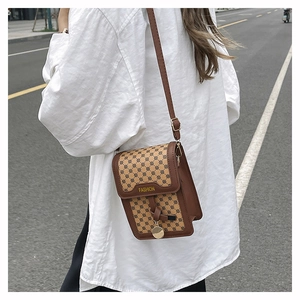 Détail d'un petit sac bandoulière marron vintage avec pendentif doré et logo fashion