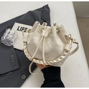 Dettaglio del secchiello crema con chiusura a coulisse e manico intrecciato stile urbano