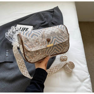 Detailed close-up of landscape jacquard fabric and brown leather trim on the shoulder bag