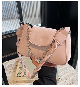 Close-up of pink crossbody bag with silver flower chain and embossed brand logo