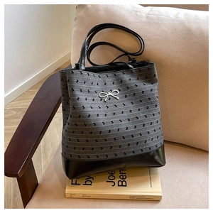 Detail view of the gray patterned jacquard tote with silver bow and black leather bottom