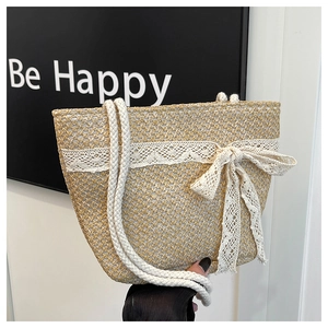Detail of hand-woven straw beach bag featuring delicate lace bow and soft cotton rope handle