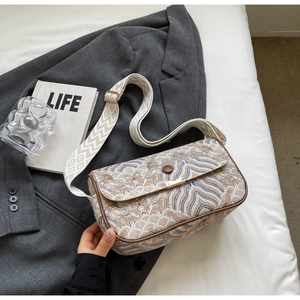 Detail of embroidered wave patterns on stylish crossbody bag with wide shoulder strap