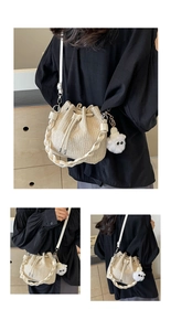 Detail of woven straw bucket bag with drawstring closure and plush monster charm
