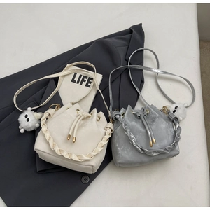 Detail of drawstring bucket bags with braided handles and cute plush monster charms