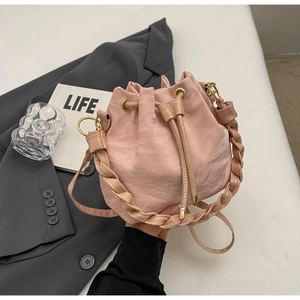 Dettaglio borsa a secchiello rosa con manico intrecciato e metallo dorato su abito grigio