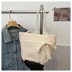 Close-up of beige woven straw tote bag featuring white lace trim and large bow detail