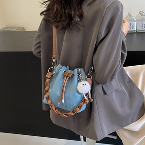 Light blue denim drawstring bucket bag with leather handle and monster charm accessory