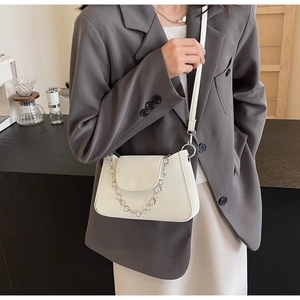 White PU leather crossbody bag with silver flower chain shown on a grey blazer outfit