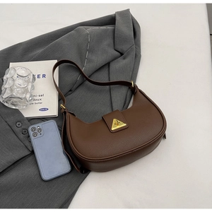 Gros plan du sac en cuir marron foncé avec boucle triangulaire dorée et grain de litchi