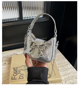 Gros plan d'un sac à main argenté à paillettes avec nœud métallique et bandoulière