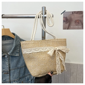 Detail of beige straw beach bag featuring delicate lace trim and knotted ribbon accent