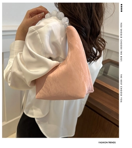 Close-up of pink ruched shoulder bag featuring marble bead handle on model