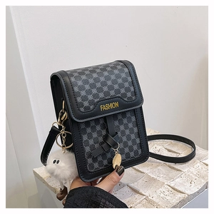 Détail d'un petit sac bandoulière vertical avec motif rétro et breloque monstre en peluche