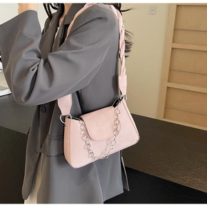 Detailed view of pink shoulder bag featuring woven strap and floral metal chain accessory