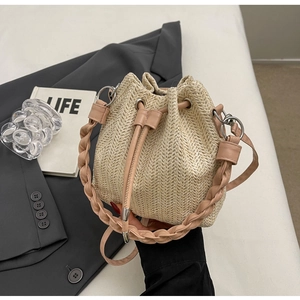 Detail of straw bucket bag with pink leather trim, braided handle and drawstring closure