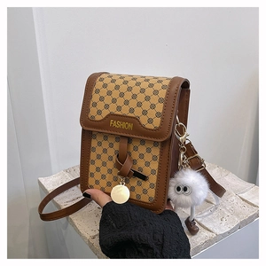 Détail d'un petit sac à bandoulière marron rétro avec un pompon blanc en peluche doux
